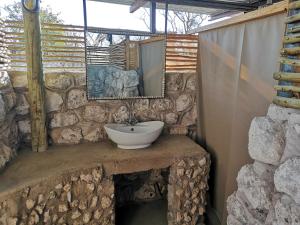 a stone bathroom with a sink and a mirror at Etosha Village Campsite in Okaukuejo