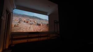 uma grande tela de televisão com uma pintura de um deserto em Hotel Cineplex em Coimbatore