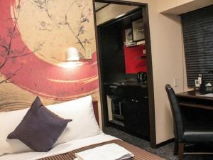 ein Hotelzimmer mit einem Bett, einem Schreibtisch und einem Spiegel in der Unterkunft HOTEL LiVEMAX Kyoto Ekimae in Kyoto