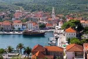 a boat in a body of water next to a town at Apartments Rubinić in Jelsa