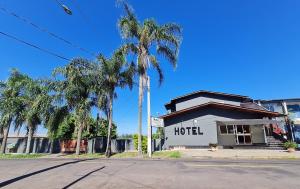 a hotel with palm trees in front of a building at Hotel Pousada Sinos in São Leopoldo