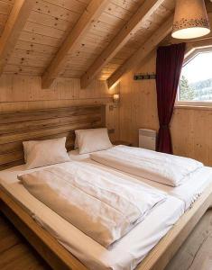 uma grande cama branca num quarto de madeira com uma janela em Chalet Claassen em Brandstätter