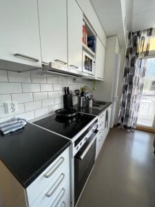 a kitchen with white cabinets and a black counter top at Hostel Teopolis in Tampere