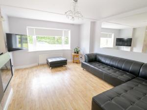 sala de estar con sofá de cuero negro en Kilkeeran Lodge, en Partry