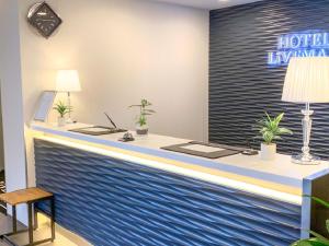 a reception desk in a hotel lobby with a blue wall at HOTEL LiVEMAX Okayama West in Okayama