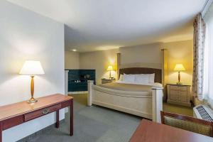 ein Hotelzimmer mit einem Bett, einem Schreibtisch und einem Tisch in der Unterkunft Baymont by Wyndham Omaha SW in Omaha