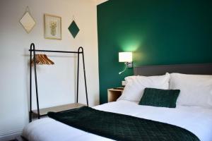 ein Schlafzimmer mit einem Bett mit einer grünen Wand in der Unterkunft Hot Tub, Free Parking, Near Shops & Restaurants, Location 1m to City in Jesmond