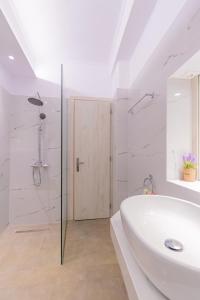 a white bathroom with a shower and a sink at Flora's Apartment! in Zakynthos Town