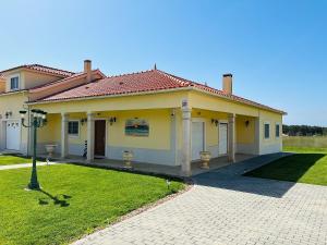 uma pequena casa amarela com um jardim de relva em Antonio's Captain House close to beaches em Atouguia da Baleia