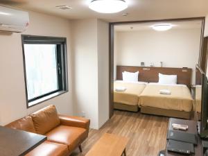 una camera con due letti, un divano e uno specchio di HOTEL LiVEMAX BUDGET Nagoya Shinkansen-guchi a Nagoya