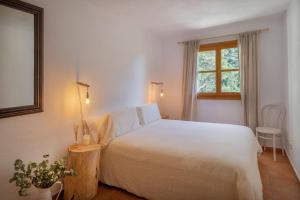 a bedroom with a white bed and a window at Casa Mistral, Un paraíso de Mar y Montaña in Valldemossa