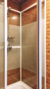 a shower with a glass door in a bathroom at Domki nad morzem CELLO in Ostrowo