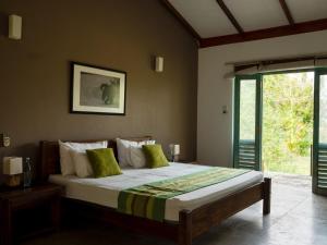 a bedroom with a large bed with green pillows at Hide Yala in Tissamaharama