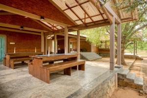 an outdoor patio with wooden tables and benches at Hide Yala in Tissamaharama