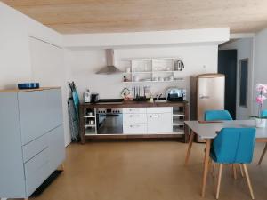 a kitchen with white cabinets and a table and blue chairs at Easy-Living Kriens Apartments in Luzern