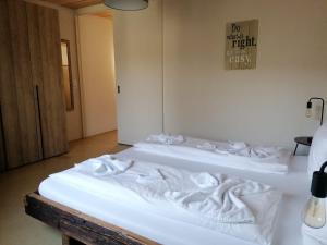 two white beds in a room with a sign on the wall at Easy-Living Kriens Apartments in Lucerne