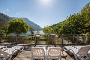 - un ensemble de chaises sur une terrasse en bois avec vue sur un lac dans l'établissement Camping Al Lago Appartamento 4, à Pieve Di Ledro
