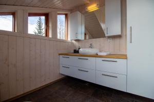 una cucina con armadi bianchi e lavandino di Gorgeous Riverside Lodge in the South of Iceland a Reykholt Altre 19 foto