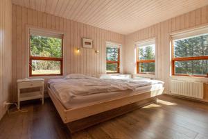 a bedroom with a large bed and two windows at Gorgeous Riverside Lodge in the South of Iceland in Reykholt