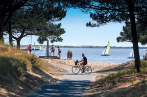 a man riding a bike on the beach at MOBIL HOME - 6 Pers - LES CHARMETTES **** in Les Mathes