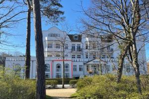 ein großes weißes Haus mit einem roten Streifen in der Unterkunft MEERBLICK-MAISONETTE Ostseebad Kühlungsborn in Kühlungsborn