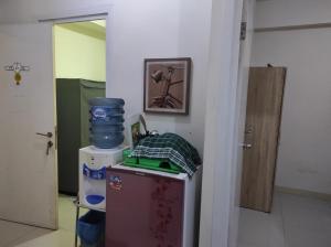 una camera con un piccolo frigorifero con una foto appesa al muro di Green Pramuka Apartment 2BR a Giacarta