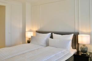 a bedroom with a bed with white pillows and two lamps at MEERBLICK-MAISONETTE Ostseebad Kühlungsborn in Kühlungsborn