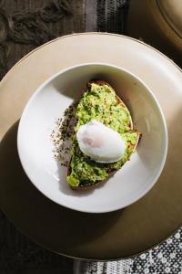 un plato blanco con un trozo de comida con un huevo. en The Saul Hotel en Tel Aviv