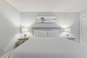 Un dormitorio con una cama blanca y dos lámparas. en Scenic Views from the balcony at Ocean Forest Plaza Condos, en Myrtle Beach