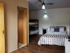 - une chambre avec un lit et un ventilateur de plafond dans l'établissement Suites Chacara Madu, à Santo Antônio do Pinhal