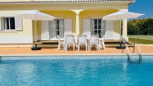 a house with chairs and umbrellas next to a swimming pool at Lara Lima by Check-in Portugal in Albufeira