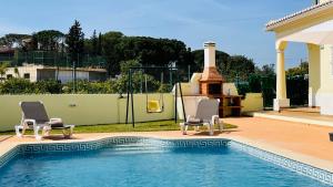 a swimming pool with two chairs next to a house at Lara Lima by Check-in Portugal in Albufeira