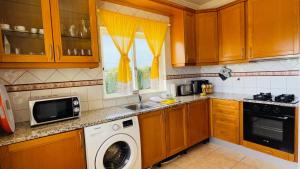 a kitchen with a washing machine and a microwave at Lara Lima by Check-in Portugal in Albufeira