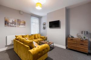 a living room with a yellow couch and a tv at Modern & Beach Location & Contractors & Leisure & Garden in Grimsby