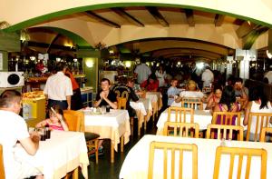 a group of people sitting at tables in a restaurant at Santa Susanna Resort in Santa Susanna