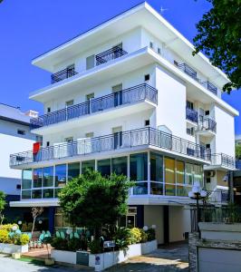 an apartment building with balconies and trees at Hotel Belmar in Rimini