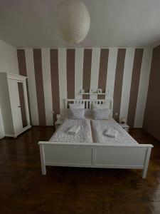 a white bed in a room with a striped wall at Ubytování Stará in Ústí nad Labem