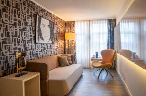 ein Wohnzimmer mit einem Sofa und einem Stuhl in der Unterkunft Albus Hotel Amsterdam City Centre in Amsterdam