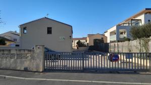 einen Zaun vor einem weißen Gebäude mit einem Haus in der Unterkunft Bel appartement à 300 mètres de la plage +parking in Valras-Plage