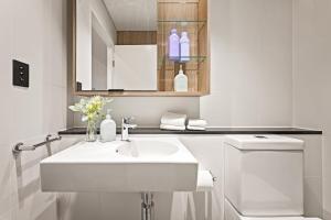 a white bathroom with a sink and a toilet at Cinema Suites Apartments by Urban Rest in Sydney