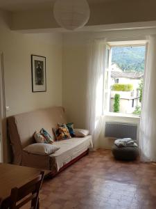 ein Wohnzimmer mit einem Sofa und einem Fenster in der Unterkunft Vista Cevenol: appartement 2 chambres in Saint-Jean-du-Gard