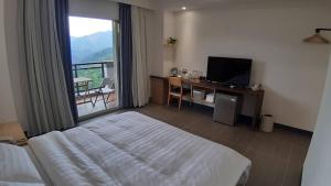 ein Schlafzimmer mit einem Bett und einem Schreibtisch mit einem Fernseher in der Unterkunft One Roll Stone Homestay in Fanlu
