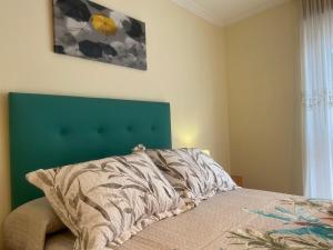 a bedroom with a bed with a green headboard at APARTAMENTO FUNCIONAL LALIN-CENTRO in Lalín