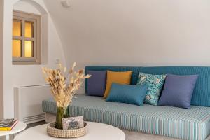 a blue couch with colorful pillows in a living room at Wine and Yard Caves in Pirgos