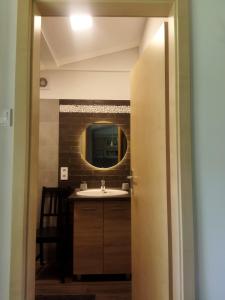 ein Bad mit einem Waschbecken und einem Spiegel in der Unterkunft Daniel Apartman in Tahitótfalu
