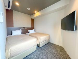 una camera d'albergo con due letti e una TV a schermo piatto di HOTEL LiVEMAX BUDGET Nagoya Shinkansen-guchi a Nagoya