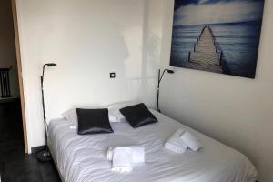 een wit bed met twee zwarte kussens erop bij Cosy 42m With Balcony Nice View And Wifi in Cannes