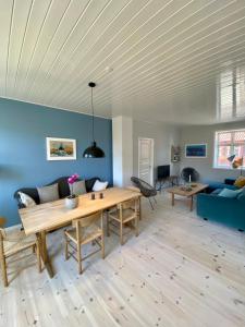 a living room with a wooden table and blue walls at Skøn ferielejlighed i midten af Svaneke udlejes, minimum 4 dage in Svaneke +7 photos