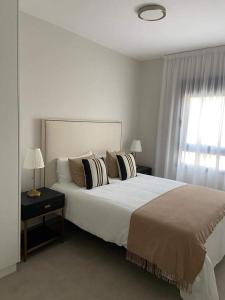 a white bedroom with a large bed and a window at Castelar Rooms in Las Palmas de Gran Canaria