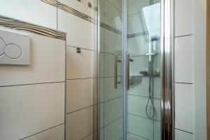a shower in a bathroom with white tiles at Ferienwohnung Alpenblick in Friedrichshafen